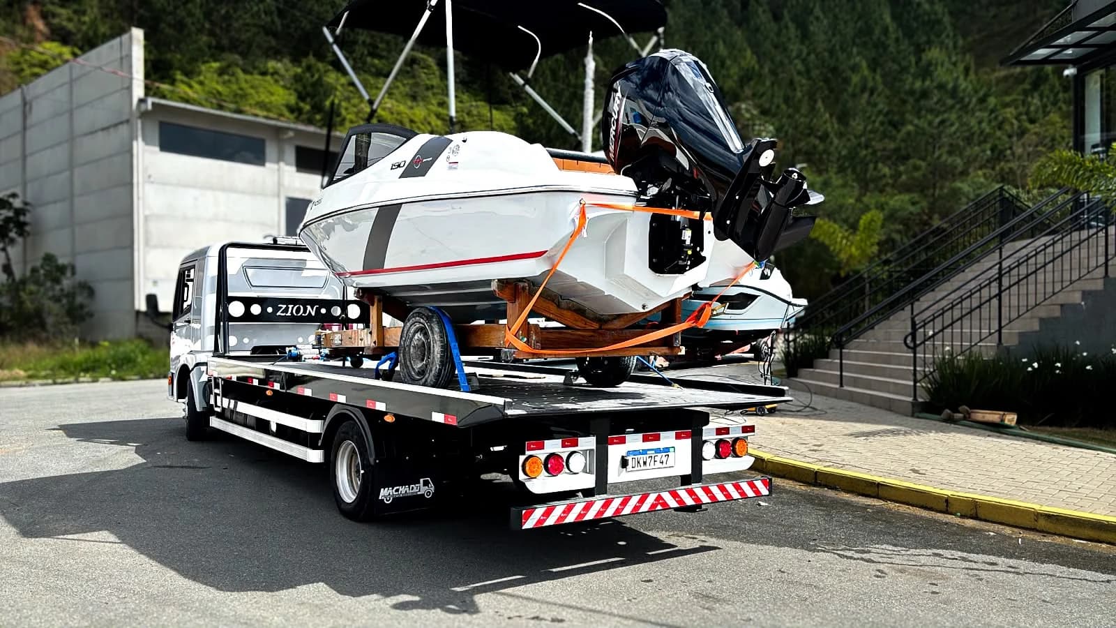 Caminhão da Zion, visto de trás, transportando um barco amarrado na plataforma